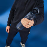 A person holds a dark blue water bottle with a flipped-open lid labeled 
