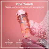 A pink water bottle, featuring rainbow designs, is held; its flip top opens one-handed. The bottle is shown against a pink background and a fuzzy pink fabric. 
