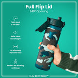 A water bottle with a full flip lid, is being held; its lid opens 240 degrees, against a teal background. The bottle features a camouflage design and the text 